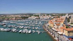 Un puerto deportivo lleno de barcos, un pueblo costero con edificios y un cielo despejado.