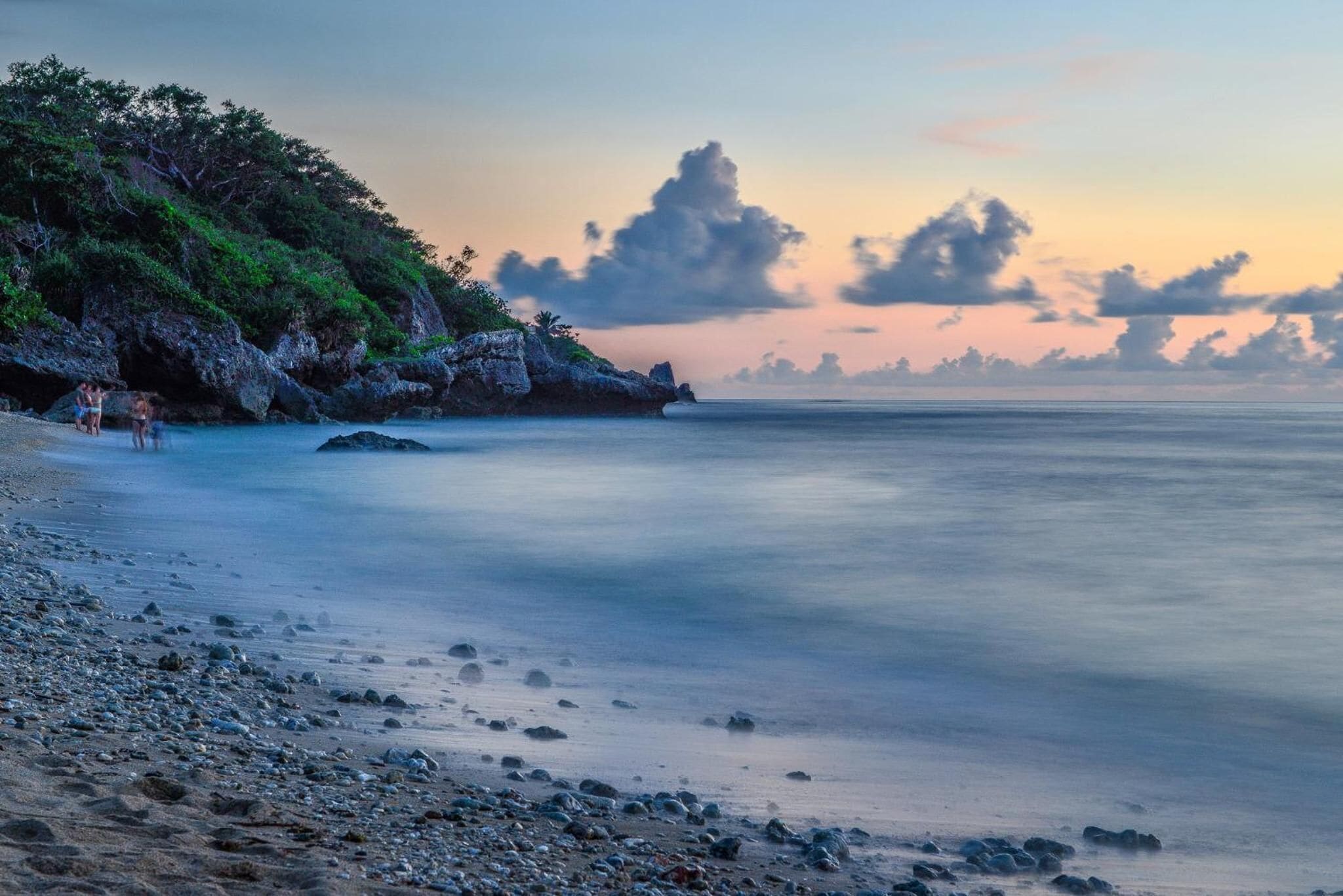 A beach with rocky terrain and calm water.