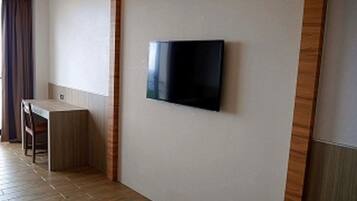 Una habitación con televisión de pantalla plana en la pared, un escritorio de madera y una silla.