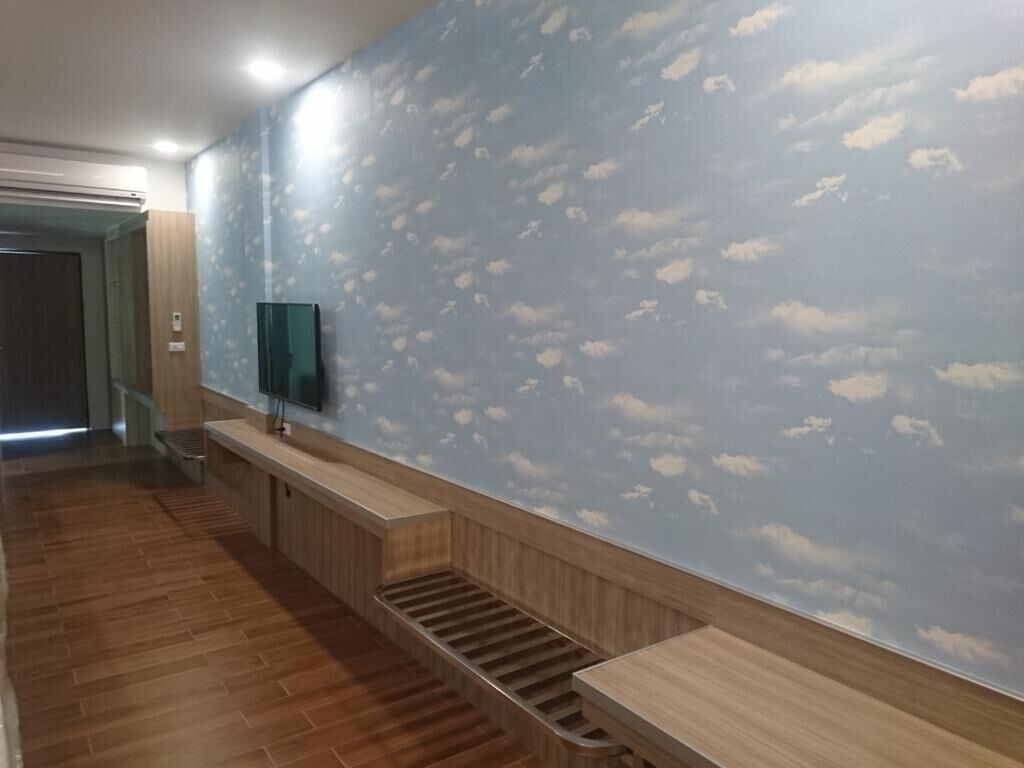 Un pasillo con un banco de madera, una escalera y un muro con diseño de nubes.