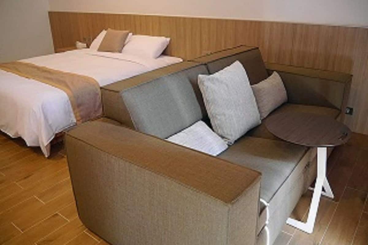 A hotel room with a bed, a sofa, and a small table.