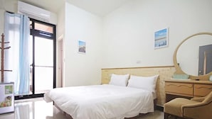A hotel room with a bed, a desk, a chair, a mirror, and a window with curtains. - Haifeng B&B (Jincheng)