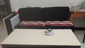 A compact room with a small table, a sofa, and a cabinet with drawers. - Haifeng B&B (Jincheng)