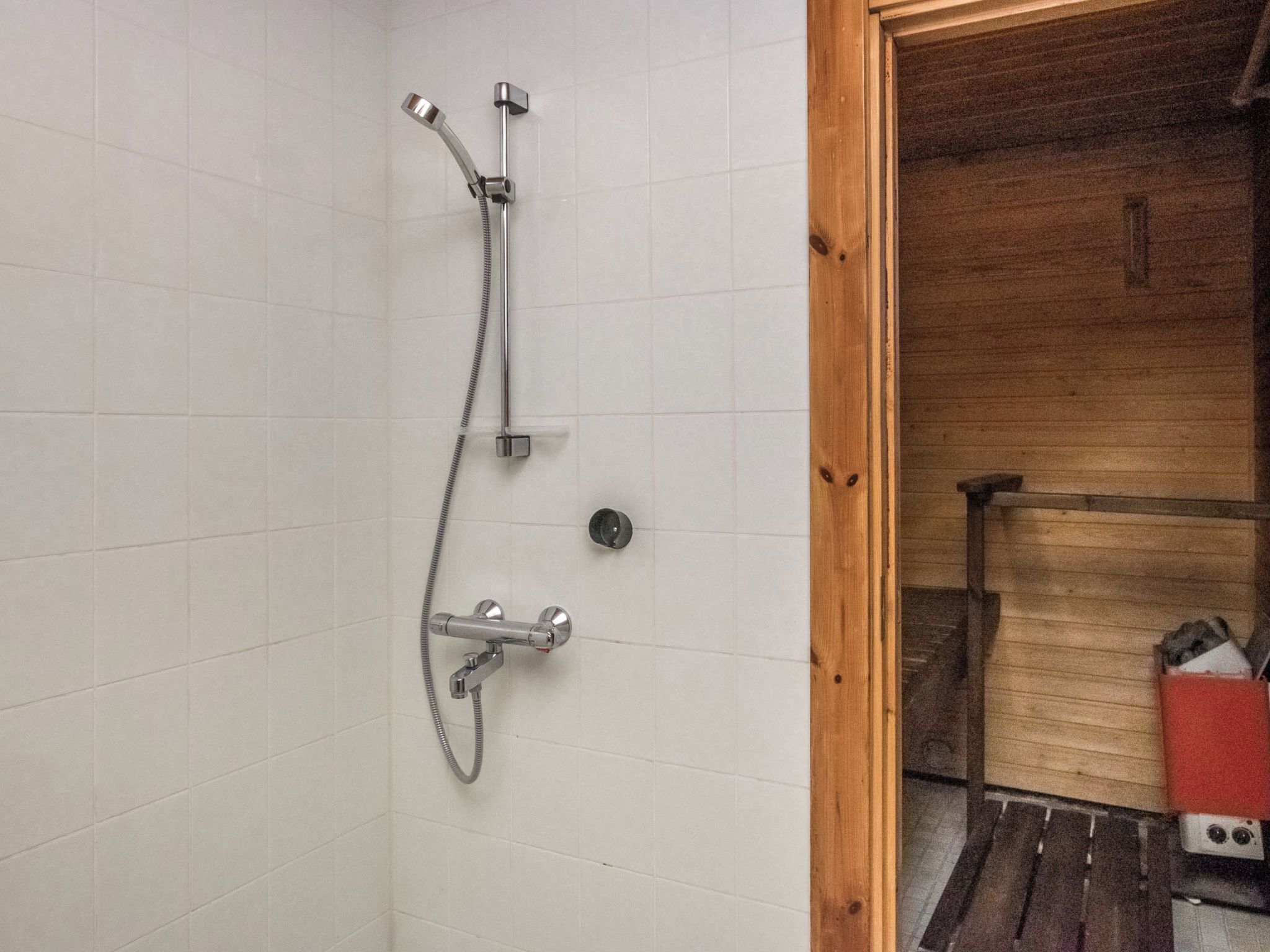 A shower with a handheld showerhead and a wall-mounted faucet.