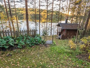 Une cabane dotée d’une terrasse en bois, entourée d’une clôture en bois et d’une végétation luxuriante.