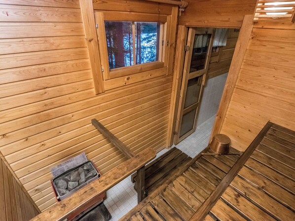 L’intérieur d’un chalet en bois, avec une fenêtre, une cheminée et un banc en bois.