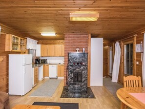 A compact kitchen with wooden cabinets, a refrigerator, a microwave, and a built-in stove. - Aurinkorinne by Interhome (Punkaharju)