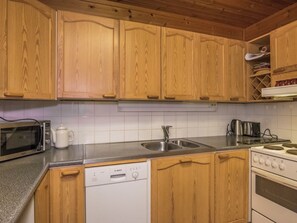 Une cuisine avec des meubles de rangement en bois, un four à micro-ondes, un lave-vaisselle, un évier et une cuisinière.