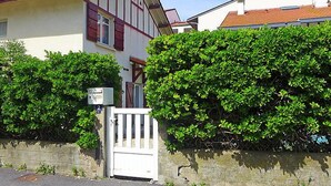 A two-story house with a white facade and red shutters, surrounded by dense green hedges. - Jean Michel by Interhome (Capbreton)