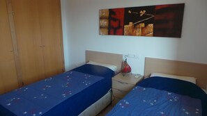 A room with two single beds, a wooden wardrobe, a nightstand with a lamp, and a painting on the wall. - Villa With Pool, Air Conditioning and WiFi on a private 18 hole golf course. (Torre-Pacheco)