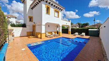 A two-story house with a swimming pool, outdoor seating, and a well-maintained garden.
