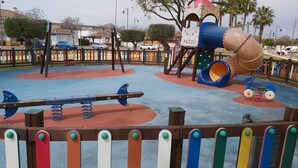 A playground with a seesaw, a slide, and a climbing structure.