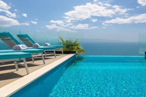 A clear blue pool with lounge chairs and a palm plant, overlooking the sea. - Luxury Villa Riva with Infinity Pool (Okrug Gornji)