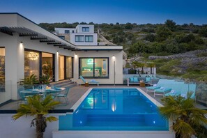 A modern house with a swimming pool, outdoor seating, and a view of the surrounding landscape. - Luxury Villa Riva with Infinity Pool (Okrug Gornji)