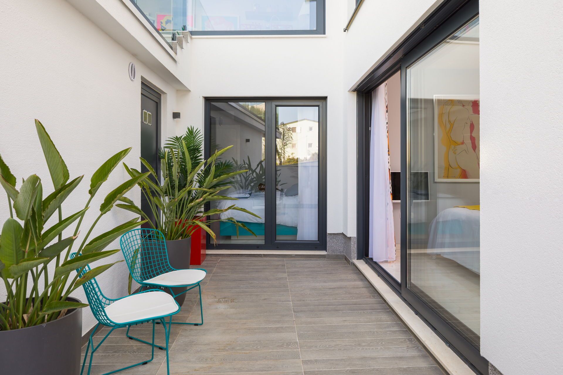 Eine moderne Außenpatio mit Topfpflanzen, eine Glastür zum Pool und Blick auf den Poolbereich.