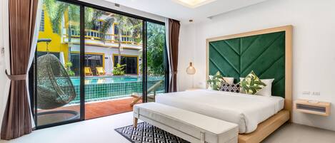 A modern bedroom with a large bed, a bench, a bedside table, and a view of a pool and outdoor area.