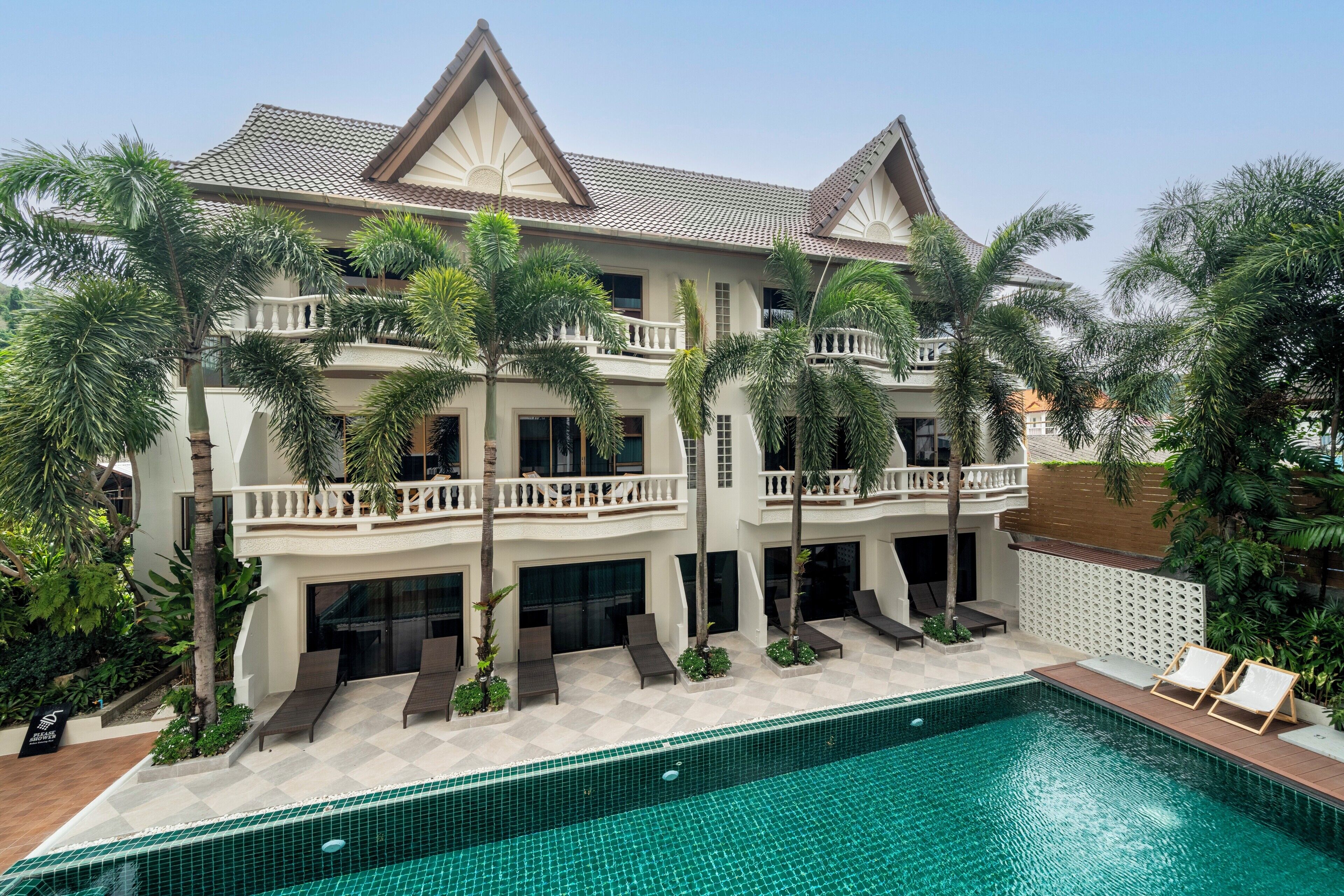 A large, multi-story hotel with a swimming pool, balconies, and lush landscaping.