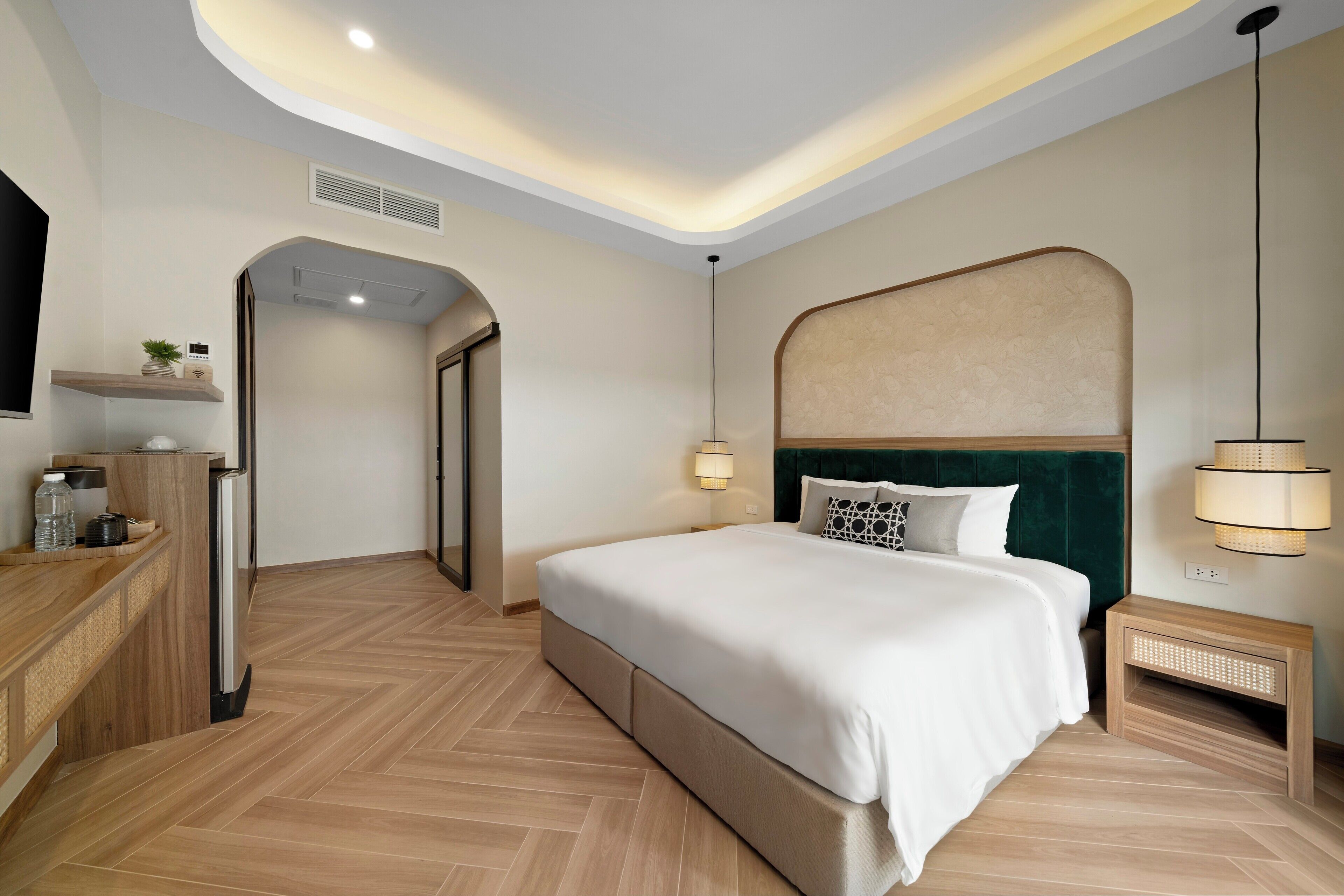 A modern bedroom with a large bed, bedside lamps, a wooden nightstand, and a built-in bench.