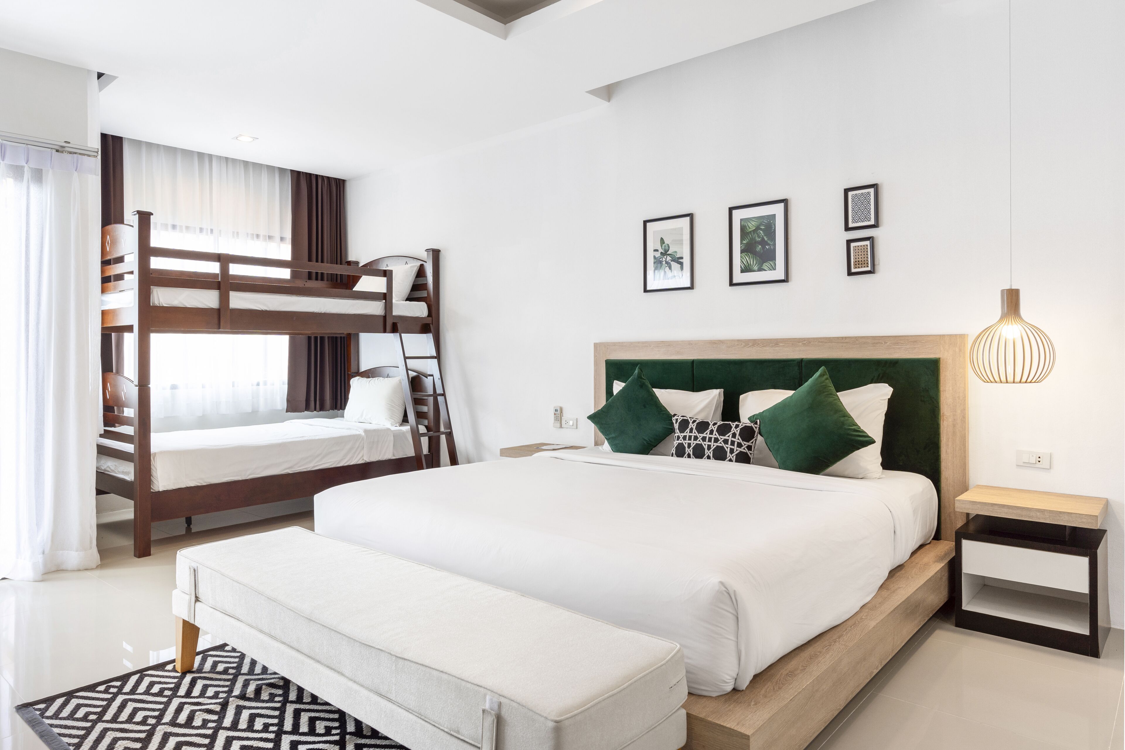 Ein modernes Hotelzimmer mit einem großen Bett, einem kleineren Etagenbett, einem Nachttisch und einem Beistelltisch.