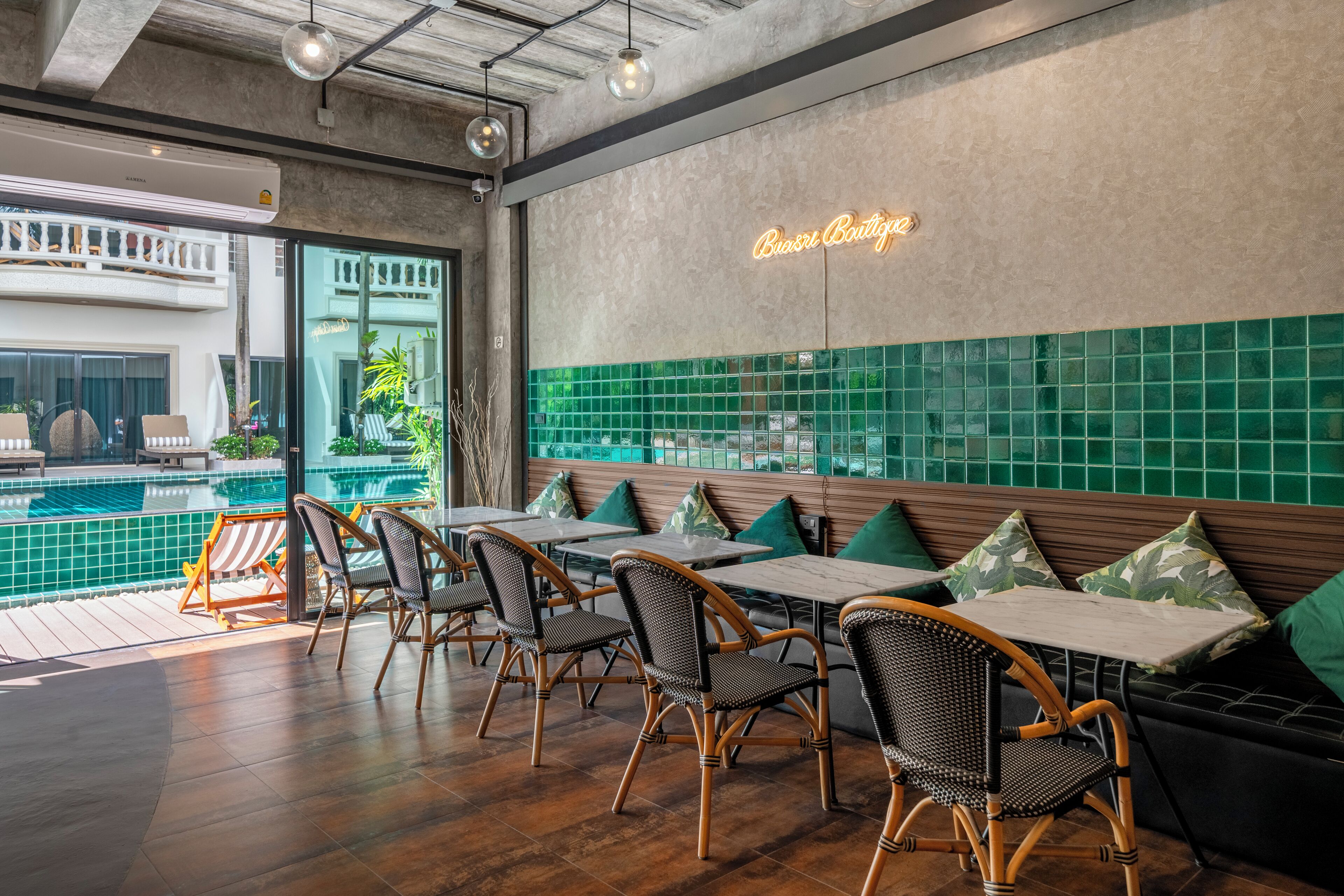 A restaurant with outdoor seating, a pool view, and a neon sign.