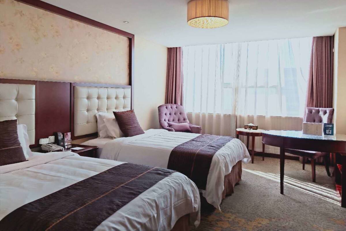 Une chambre d’hôtel avec deux lits, un bureau et une chaise.