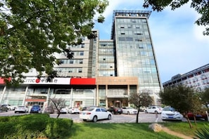 Een modern gebouw met meerdere verdiepingen, een parkeerplaats ervoor en een bord met Chinese karakters.