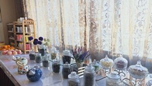 Une table sur laquelle se trouvent divers pots contenant différents objets, une chaise en bois et une bibliothèque remplie de livres et d’objets décoratifs.