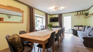 Un comedor con una mesa y sillas de madera, un sofá y un televisor montado en la pared.