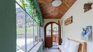 Una habitación acogedora con suelo de piedra, un banco de madera y un amplio ventanal con vistas panorámicas.