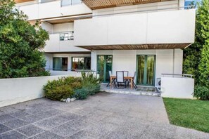 A modern two-story building with a flat roof, a patio with a table and chairs, and a small garden area. - Marina Aquamar 009 By VilamouraSun - Ground Floor (Vilamoura)