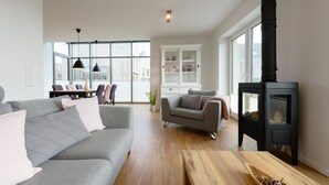Un salon moderne avec un canapé gris, une table basse en bois et une cheminée noire.