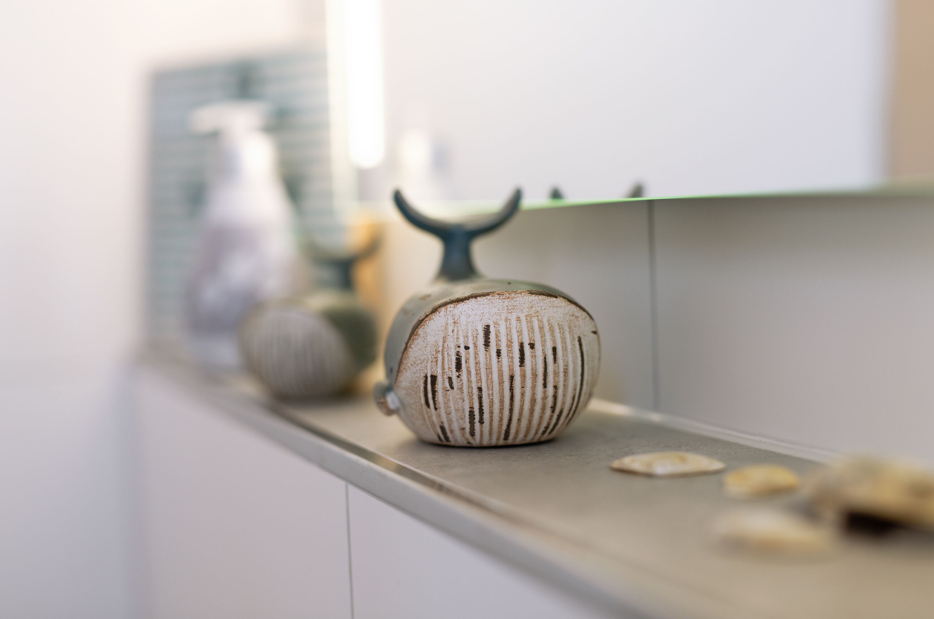 A kitchen counter with a decorative ceramic bowl and a bottle.