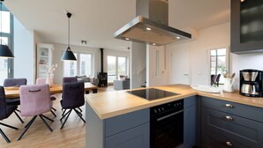 Une cuisine moderne dotée d’un îlot central, d’un four encastré et d’un coin repas avec des chaises et une table.