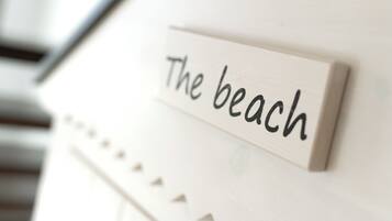 Ein Schild mit dem Schriftzug 'The beach' an einer weißen Wand.