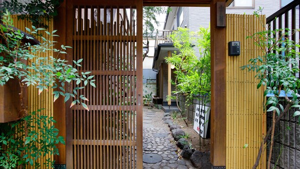 Ein traditionelles japanisches Tor, das zu einem Steinweg führt.