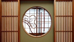 Ein traditioneller japanischer Shoji-Bildschirm mit rundem Fenster, Holzlamellen und einem Bambusvorhang.