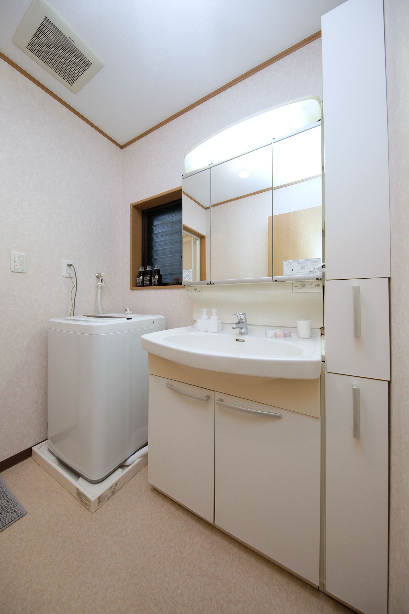 A small, clean bathroom with a sink, mirror, and a washing machine.