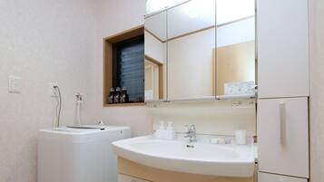 A small, clean bathroom with a sink, mirror, and a washing machine.