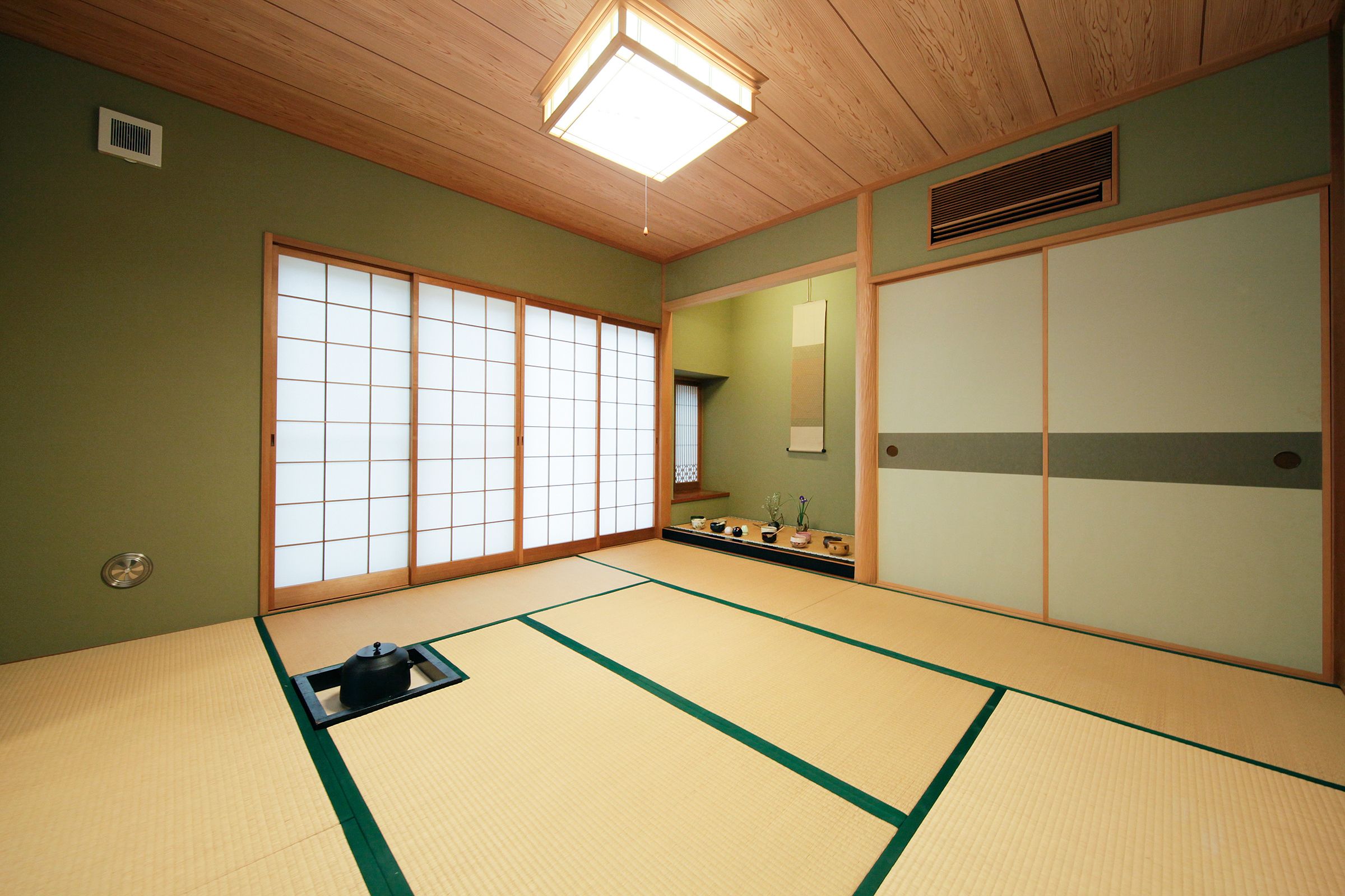 Ein Raum mit Tatami-Matten, Schiebetüren, einer Tatami-Matte, einer schwarzen Ablage und einem kleinen Tisch mit Gegenständen.