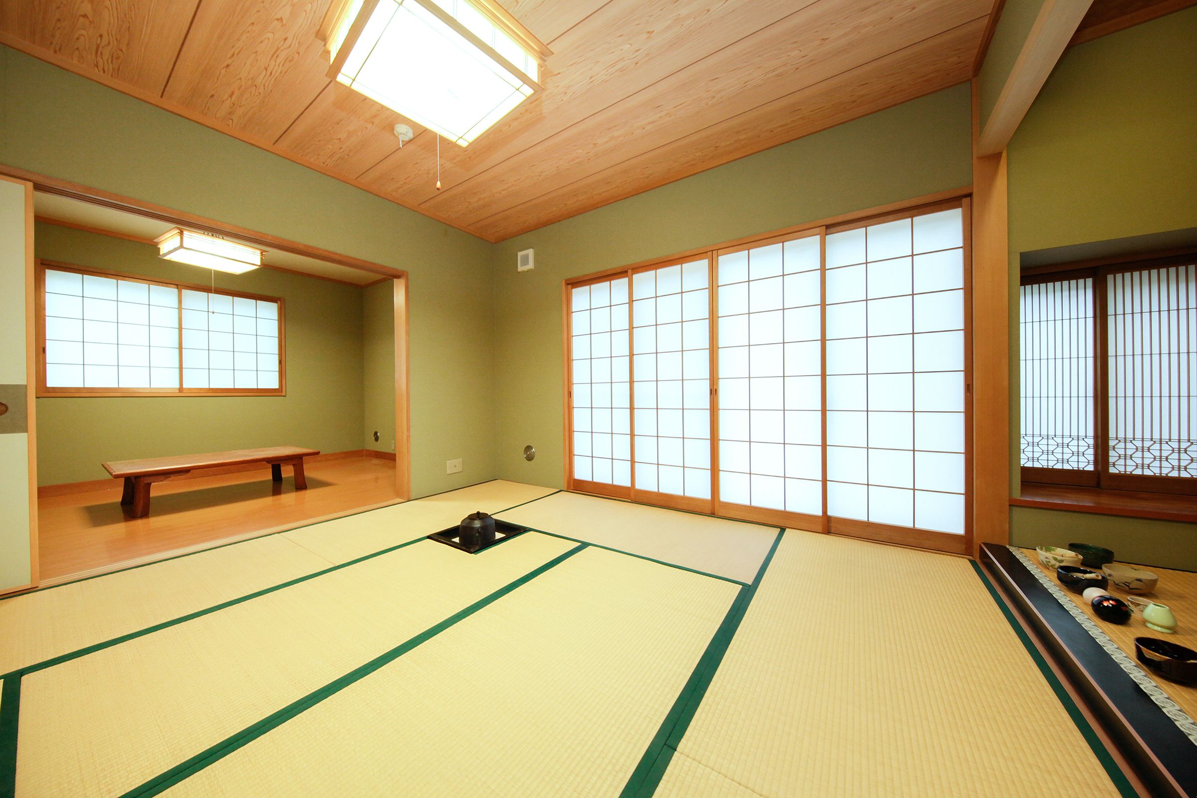 Ein Raum mit Tatami-Matten, Schiebetüren, einer Bank und traditioneller japanischer Einrichtung.