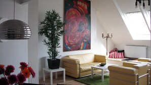 A modern living room with a yellow sofa, a white coffee table, a green rug, and a large abstract painting on the wall. - Loft above the rooftops of Berlin (Bezirk Friedrichshain-Kreuzberg)