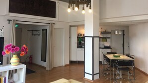 A spacious living area with a dining table, kitchen in the background, and a large window. - Loft above the rooftops of Berlin (Bezirk Friedrichshain-Kreuzberg)
