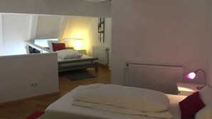 A bedroom with a bed, a nightstand, a lamp, and a radiator. - Loft above the rooftops of Berlin (Bezirk Friedrichshain-Kreuzberg)