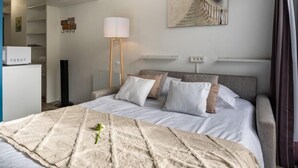 Una habitación de hotel con una cama, una mesita de noche, una lámpara, un cuadro y vistas al mar.