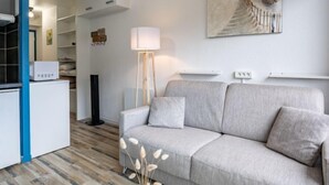 Una sala de estar moderna con un sofá gris, una lámpara de pie y un cuadro en la pared.