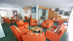 Ett hotellrum med orange soffor, en matplats med randiga stolar och ett litet bord.