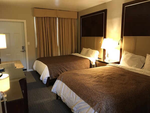 Una habitación de hotel con dos camas, un escritorio y una silla.