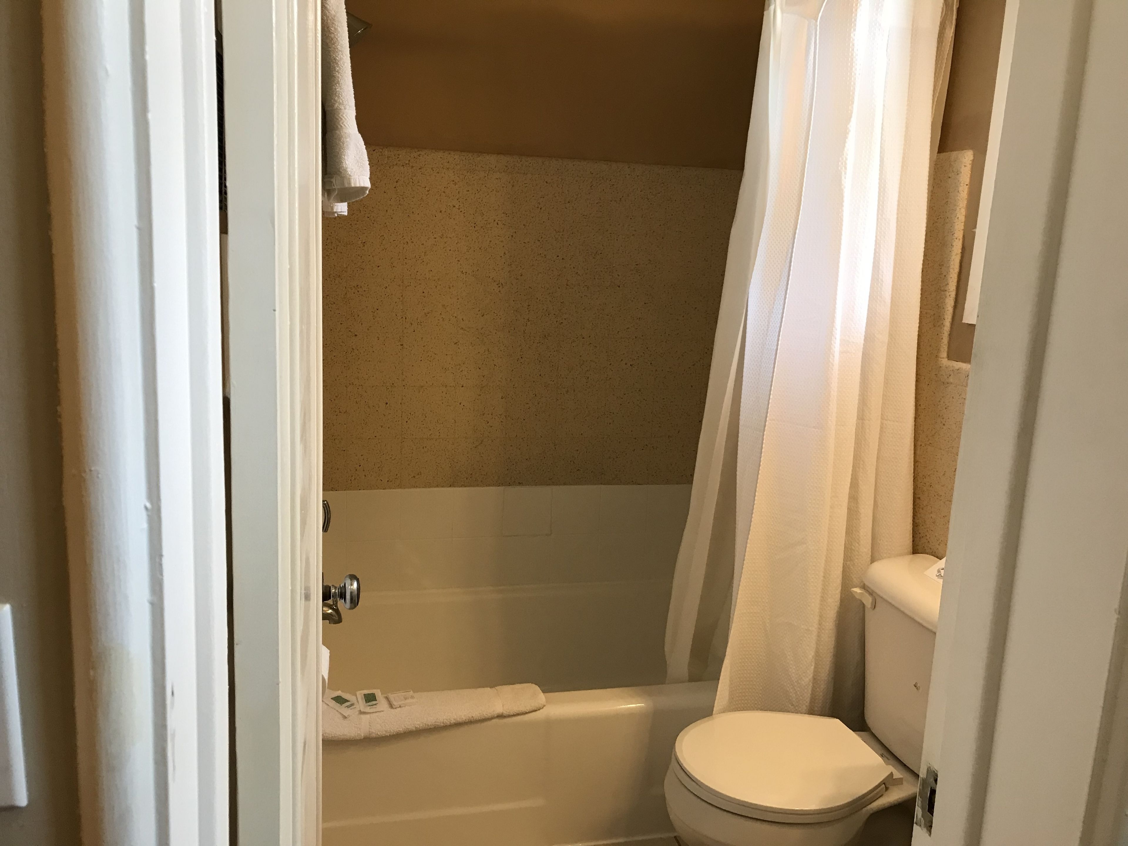 A bathroom with a bathtub, toilet, and a towel rack.