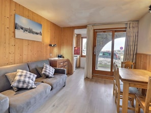 A wooden interior with a sofa, a dining table, and a kitchen area.