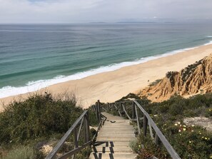 A wooden staircase leading to a beach with clear skies.